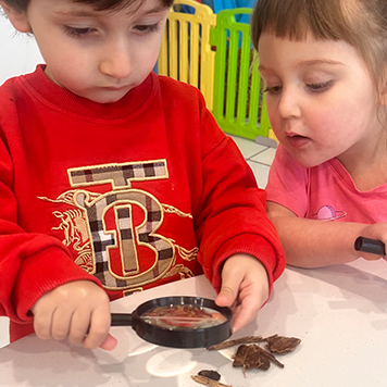 Children explooring nature with a looking glass at Annar Childcare